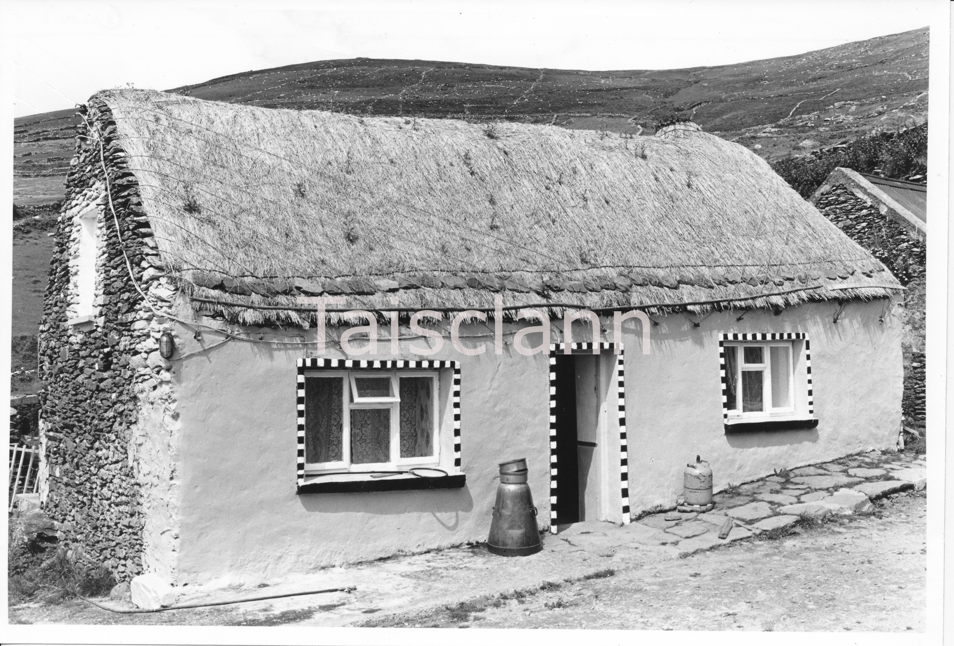 A roof held down with ropes weighted with stones and metal bars. The thatch around the small chimney is interesting.