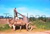 Boy filling barrel of water. Donkey and dog.