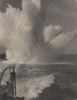 An explosion in the water behind a warship