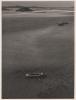 Currach with three people aboard in the middle of a bay