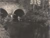 Fishing in a small river beneath an old bridge