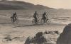 Three people cycling on the beach