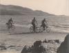 Three people cycling on the beach